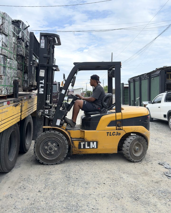 Operador da RF Metais conduzindo empilhadeira no carregamento de fardos de metal em um caminhão no pátio da empresa.